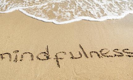 beach with the word mindfulness drawn in the sand. 